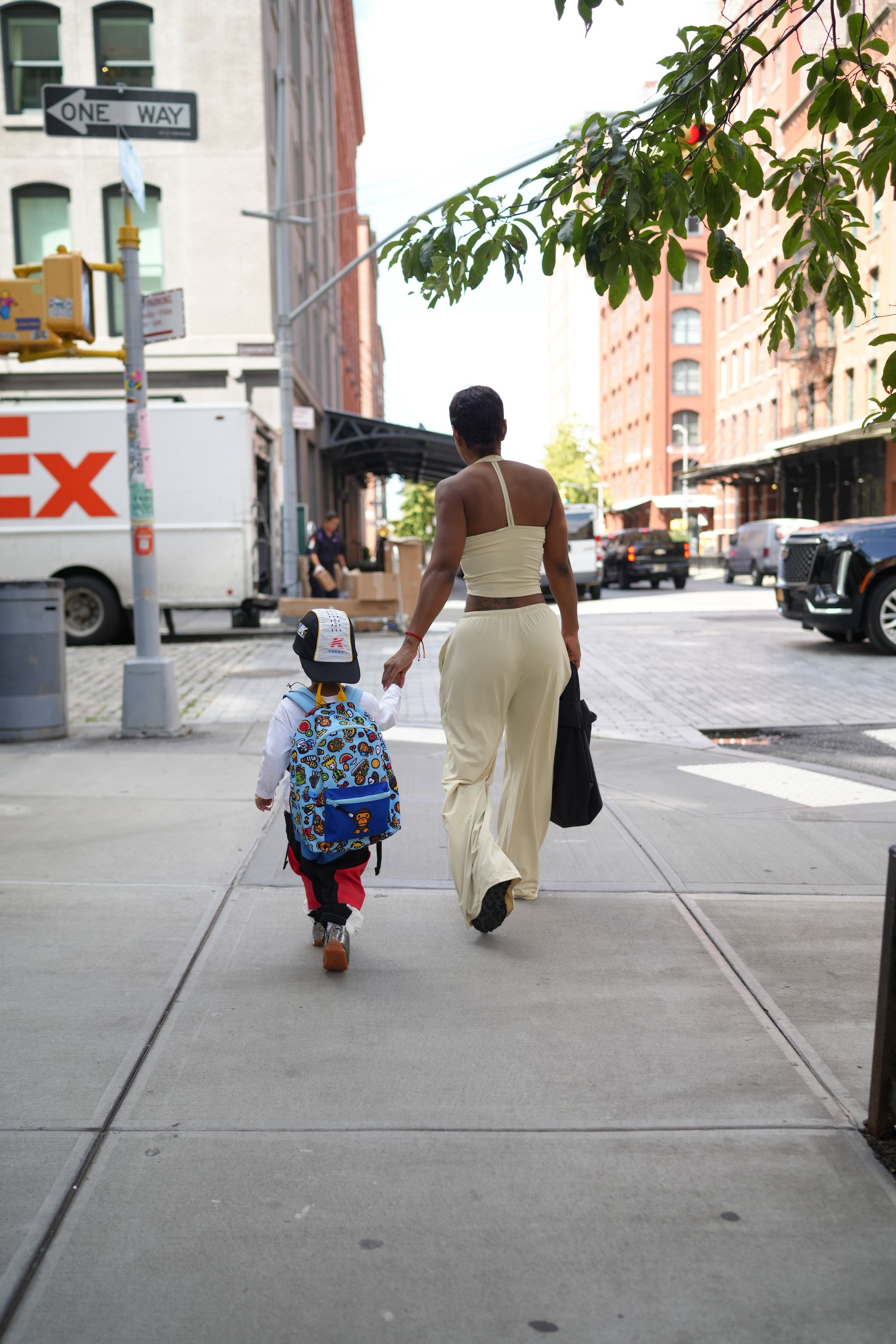 Woman walking with a child on a city street, Exxpress truck in the background