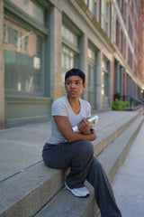 Person sitting on a sidewalk holding books in an urban setting